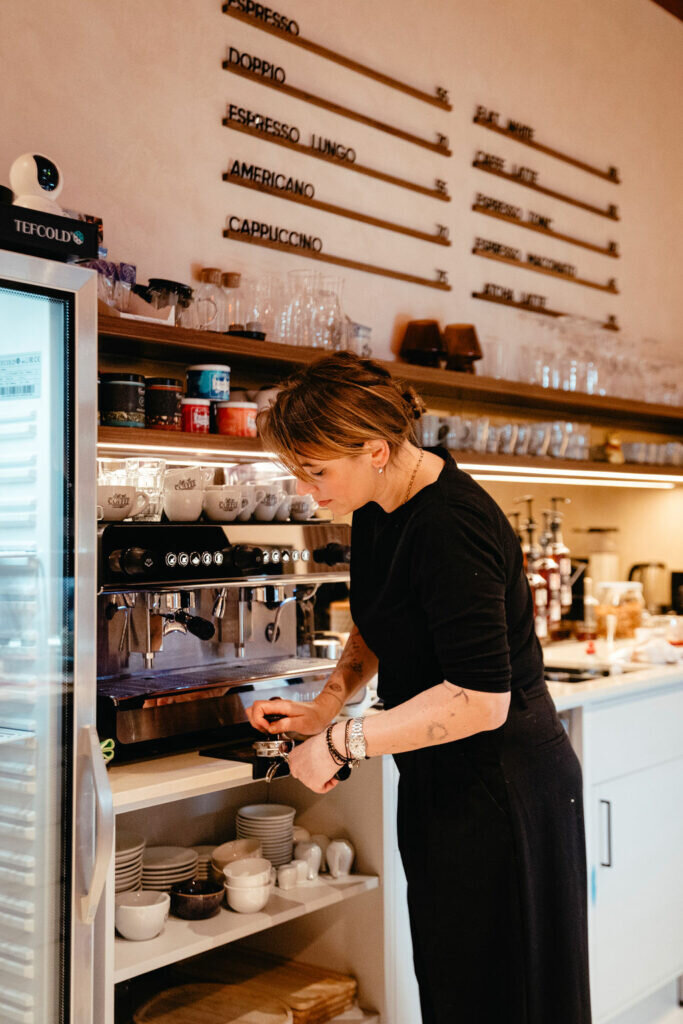 Interiér kavárny Kafky Kafé — baristka za kávovarem
